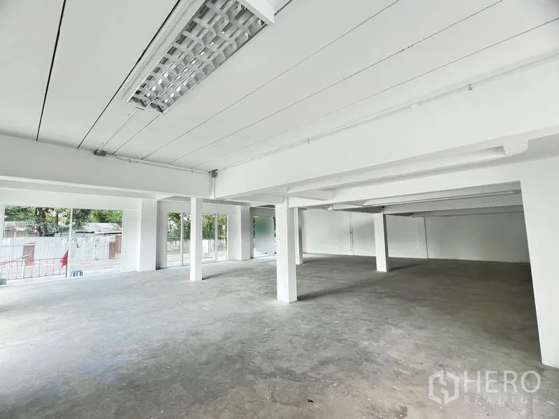 Retail Space for rent in Huai Khwang, Bangkok - Bright retail interior with large windows, white ceiling panels and structural pillars.