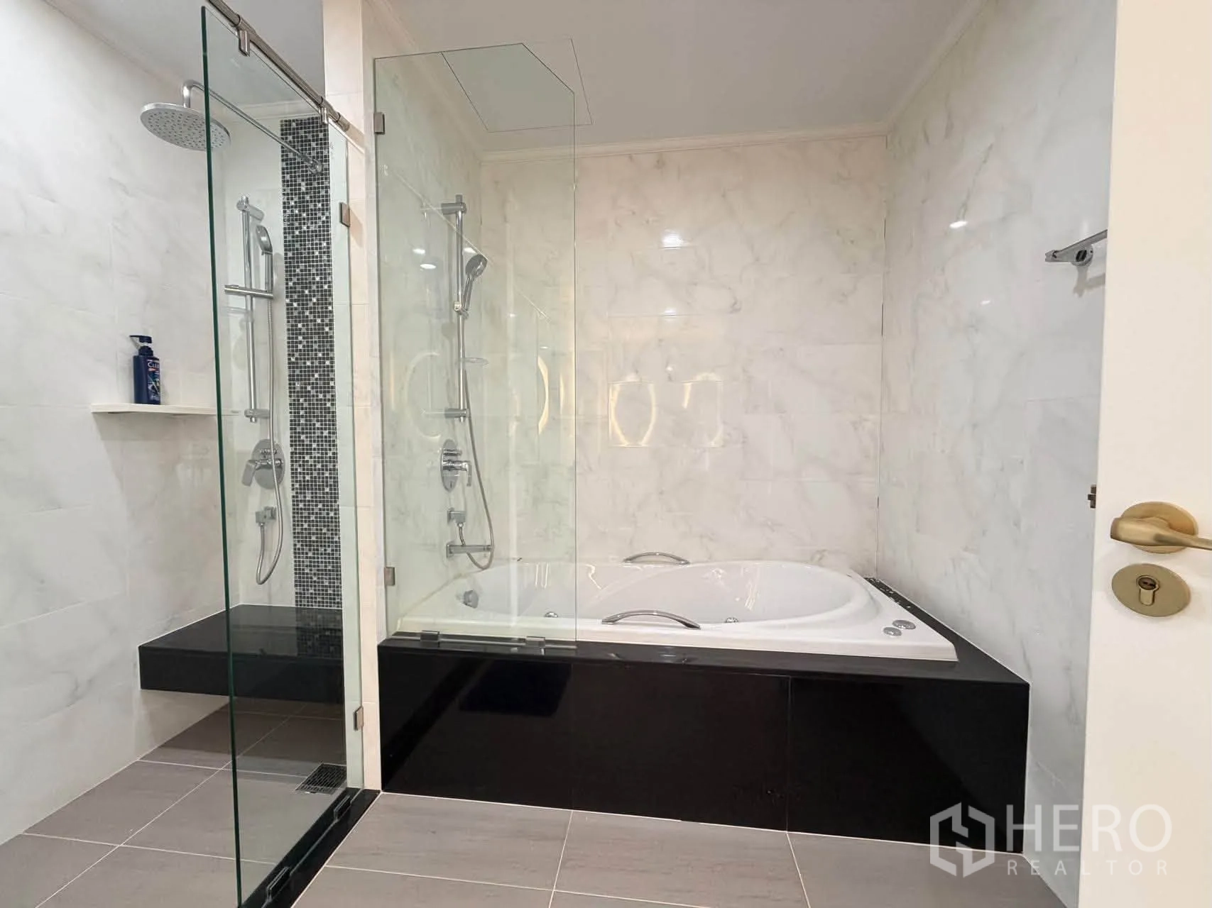 Condominium for sale in Watthana, Bangkok - Modern bathroom with glass shower and raised soaking tub on black base.