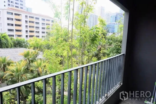 Condominium for sale in Khlong Toei, Bangkok - Balcony view over lush trees toward nearby city buildings in the Phrom Phong area.