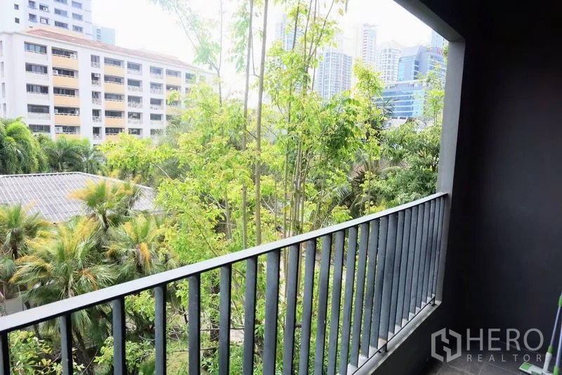 Condominium for sale in Khlong Toei, Bangkok - Balcony view over lush trees toward nearby city buildings in the Phrom Phong area.
