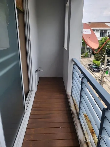 联排别墅 出租在Wang Thonglang, Bangkok - 狭长阳台，木质地板与蓝色栏杆，眺望街景