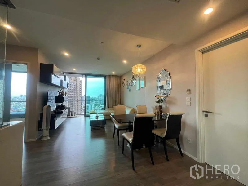 Condominium for rent in Khlong Toei, Bangkok - Spacious open-plan living–dining room facing a balcony and wide Bangkok skyline.