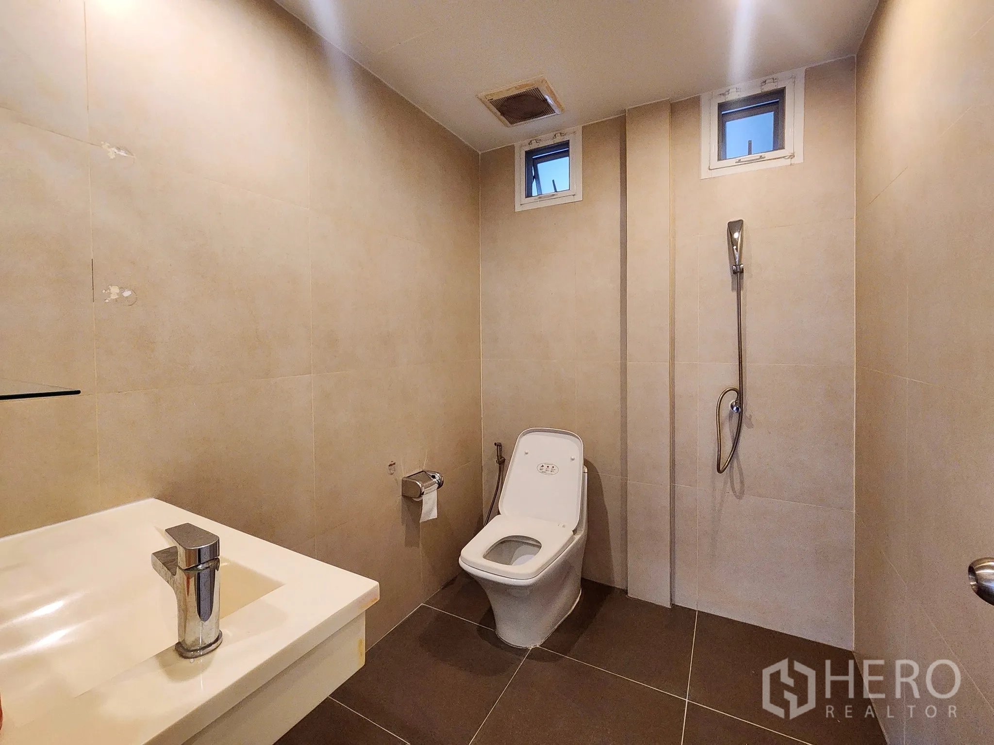 Detached House for rent in Bang Kapi, Bangkok - Ensuite bathroom with large mirror, vanity and chevron floor tiles.