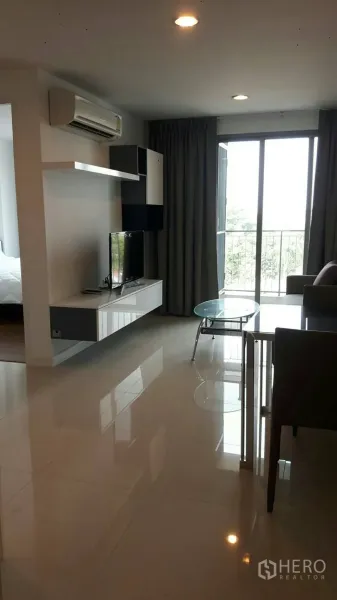 คอนโด ให้เช่าในPhaya Thai, Bangkok - ห้องนั่งเล่นสว่างพร้อมชั้นวางทีวี เครื่องปรับอากาศ และประตูบานเลื่อนออกสู่ระเบียงในคอนโดพญาไท
