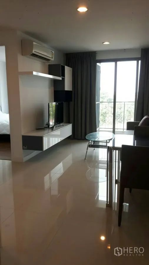 Condominium for rent in Phaya Thai, Bangkok - Bright living area with wall-mounted TV unit, air-conditioning and sliding door to a balcony in a Phaya Thai condo.