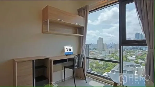 Condominium for rent in Khlong Toei, Bangkok - Work desk beside a large window with built-in shelving and expansive city views.