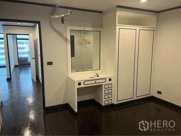 Condominium for rent or sale in Watthana, Bangkok - Dressing area with built-in vanity, wardrobe and dark wood floors in 2-bedroom condo near Phrom Phong BTS.