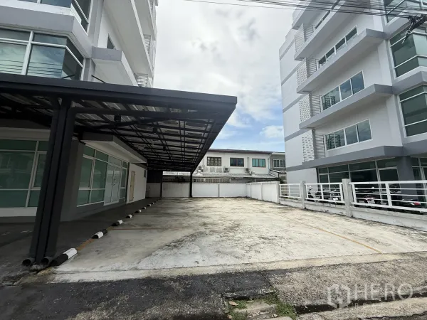 办公空间 出租在Bueng Kum, Bangkok - 现代办公楼之间的宽敞露天停车区与围栏。