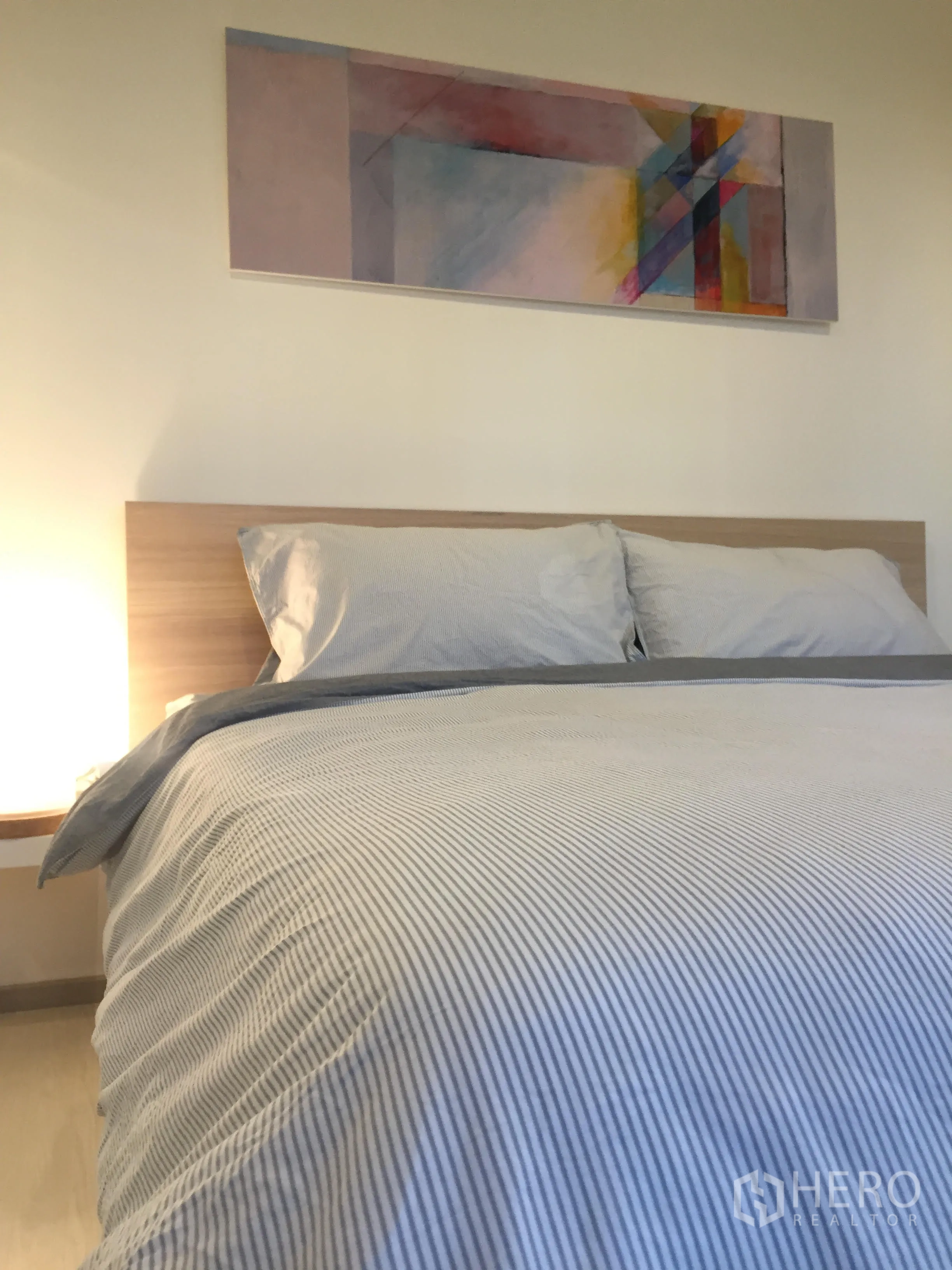 Condominium for rent in Khlong Toei, Bangkok - Bright bedroom with a double bed, wood headboard and abstract artwork above the bed.