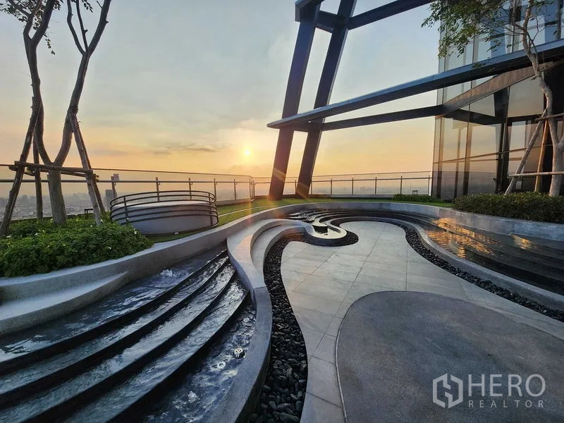 Condominium for rent - Rooftop garden terrace at sunset with flowing water features and wide Bangkok panorama.