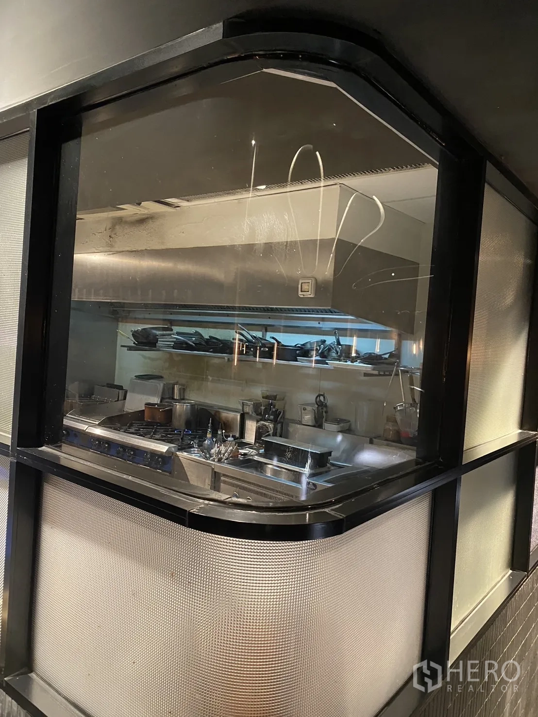 Shophouse for rent in Watthana, Bangkok - Commercial kitchen behind glass with gas range, hood and stainless equipment.