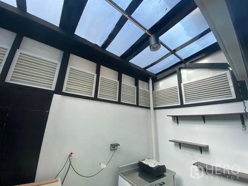 Townhouse for rent or sale in Saphan Sung, Bangkok - Semi-outdoor service area with glass roof, wall shelves and electrical outlets.