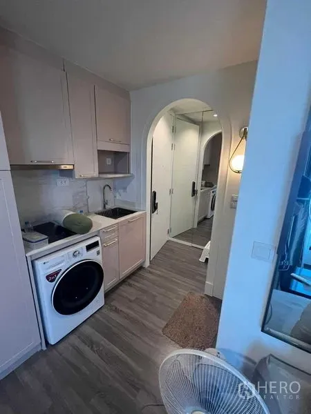 公寓 出售在Ratchathewi, Bangkok - 现代小厨房，水槽与橱柜，前置洗衣机，通向拱形走廊与镜面衣柜。