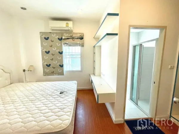 Townhouse for rent in Saphan Sung, Bangkok - Bright bedroom with white walls, queen bed, built‑in desk, air conditioner and door to an ensuite.