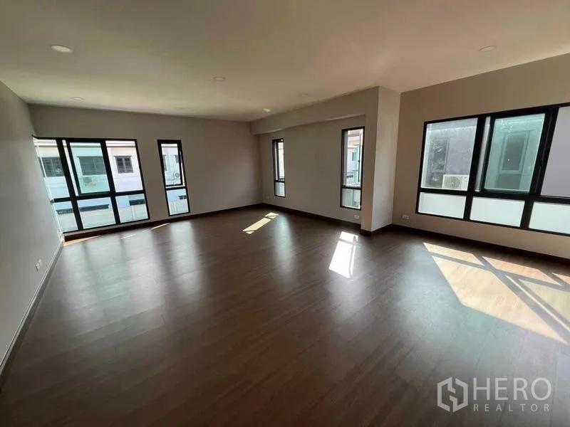 独立式住宅 出租在Khlong Sam Wa, Bangkok - 宽敞客厅，木地板与多扇黑框窗户，采光充足。