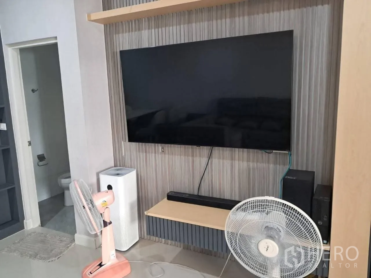 Townhouse for rent in Bang Kapi, Bangkok - Living area media wall with mounted flat-screen TV beside a bathroom door.