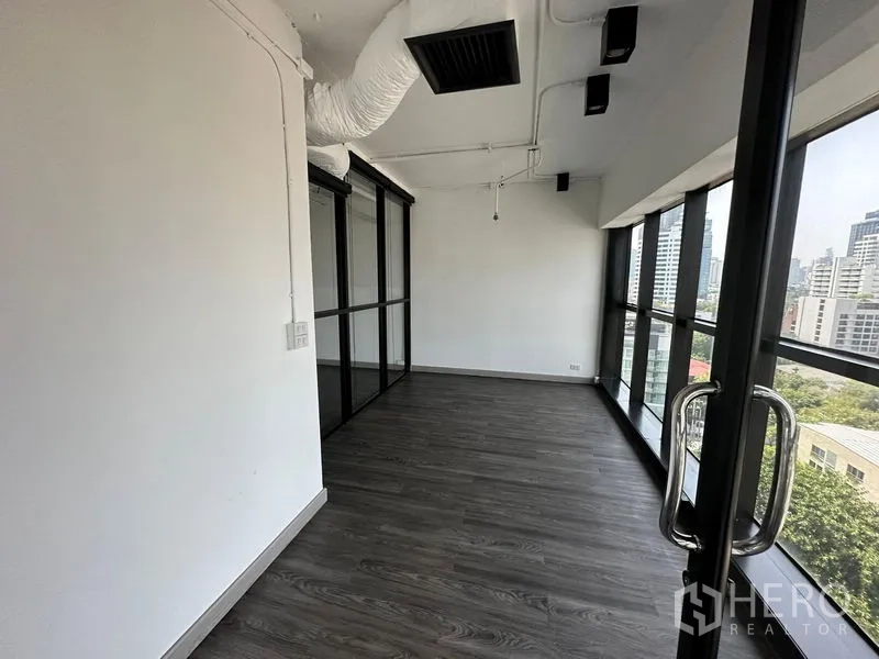 办公空间 出租 - 狭长会议或休闲区，整面落地窗与深色地板。