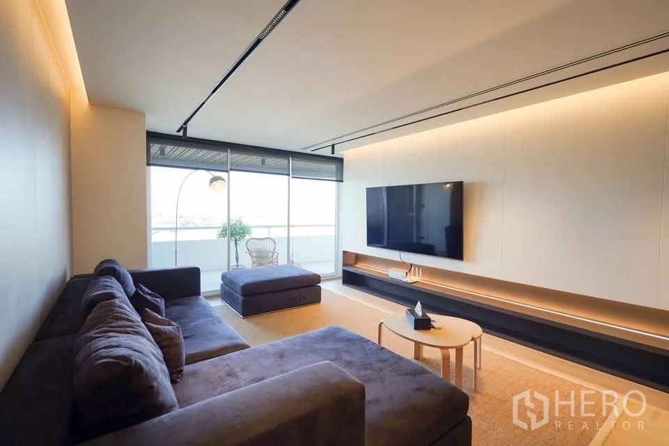 公寓 出租在Bang Phlat, Bangkok - 采光充足的客厅，转角沙发与壁挂电视，连接到阳台。
