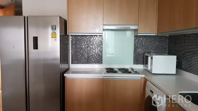 Condominium for rent in Ratchathewi, Bangkok - Fitted kitchen with wood cabinets, mosaic backsplash, electric cooktop, stainless refrigerator, microwave and washer.