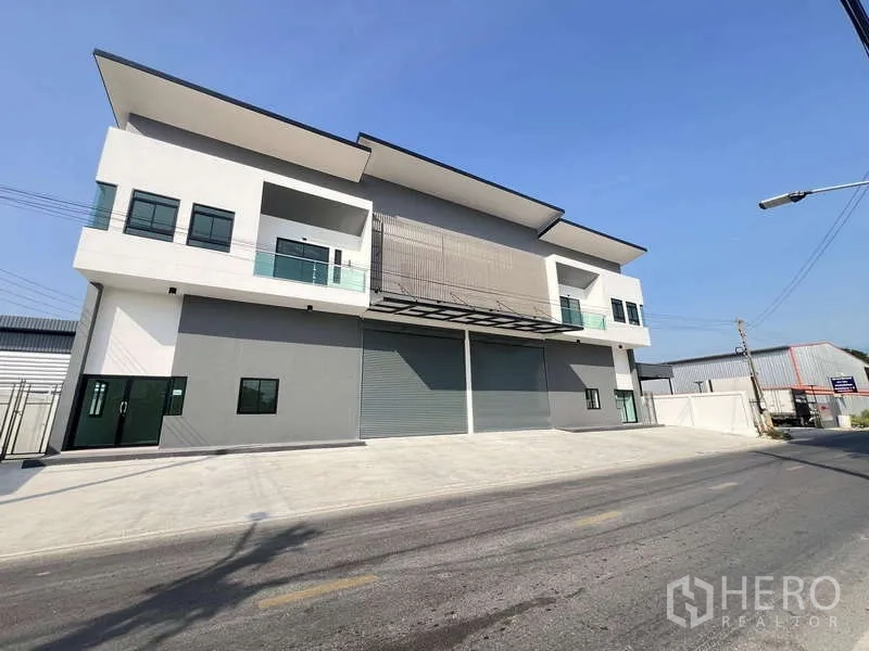 Warehouse for rent or sale - Wide‑angle street view of a contemporary warehouse block with a large concrete forecourt.