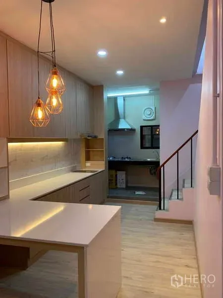 Townhouse for rent - Modern kitchen with pendant lights, light wood cabinetry, breakfast counter and staircase to the upper floor.