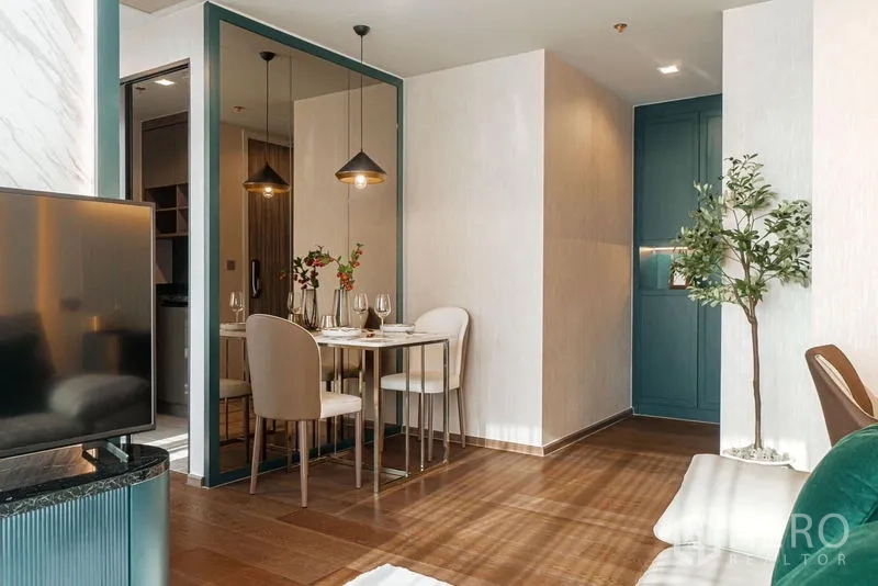 Condominium for rent in Khlong Toei, Bangkok - Open-plan dining and living space with a large mirror and modern pendant lighting.