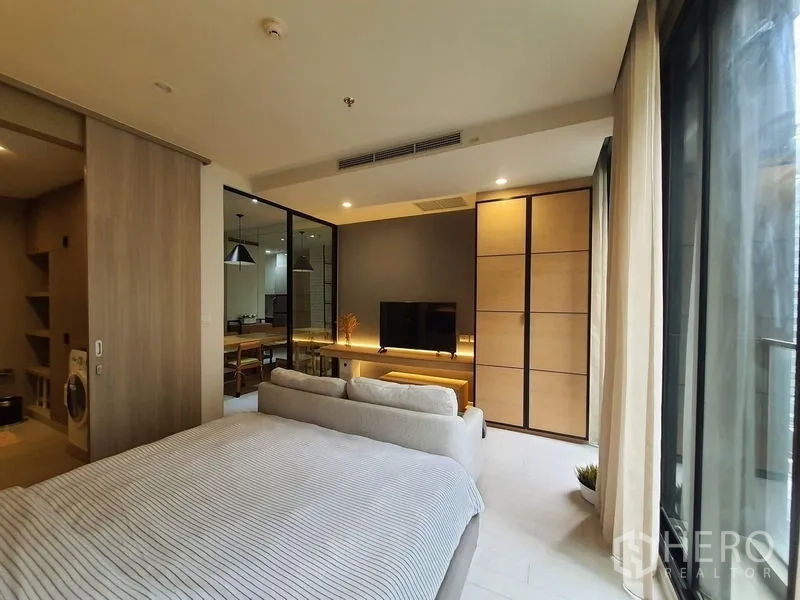 公寓 出租在Pathum Wan, Bangkok - 卧室设电视墙与大衣柜，推拉玻璃门通向餐区，自然光充沛。