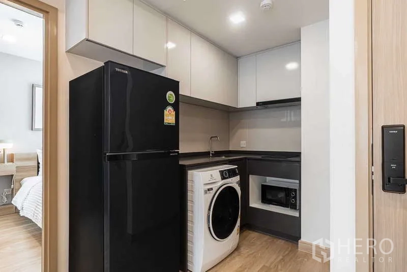 Condominium for rent - Modern L-shaped kitchen with black refrigerator, washer and built-in microwave.
