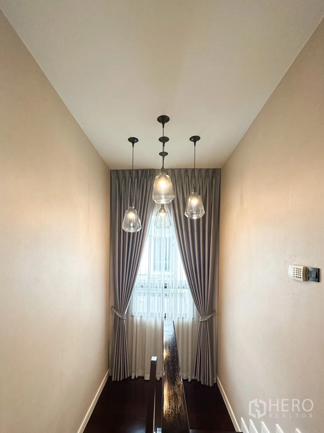 Detached House for rent or sale in Bang Kapi, Bangkok - Stair landing with glass pendant lights and curtained window.