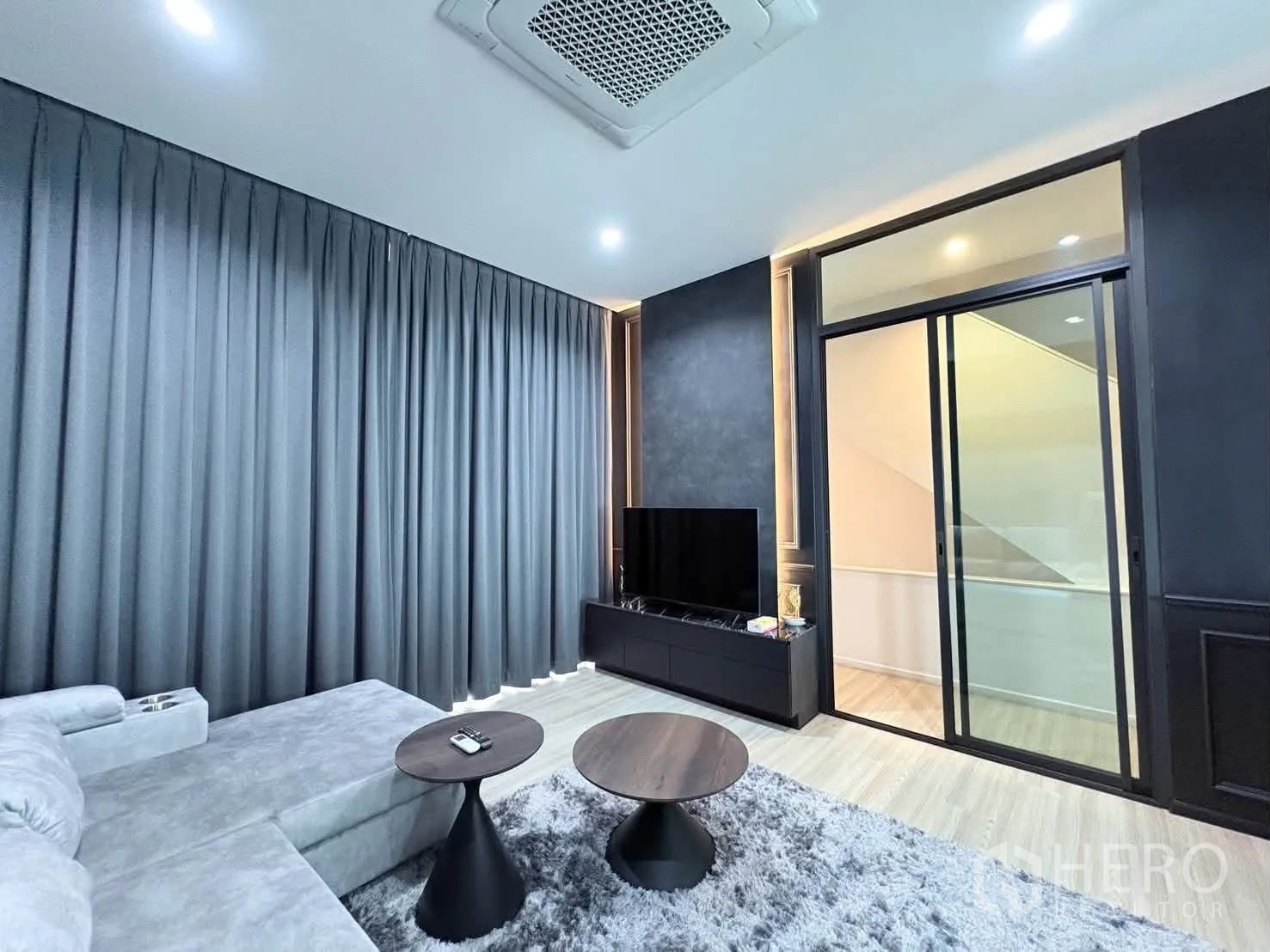 独栋房屋 for rent in Saphan Sung, Bangkok - 起居室设大沙发、电视柜、推拉玻璃门与厚窗帘。