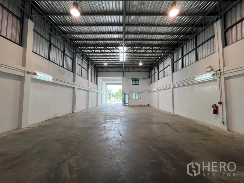 货栈 出租在Bang Phli, Samut Prakan - 仓库内部朝向装卸入口，高挑天花、照明与小型办公室。