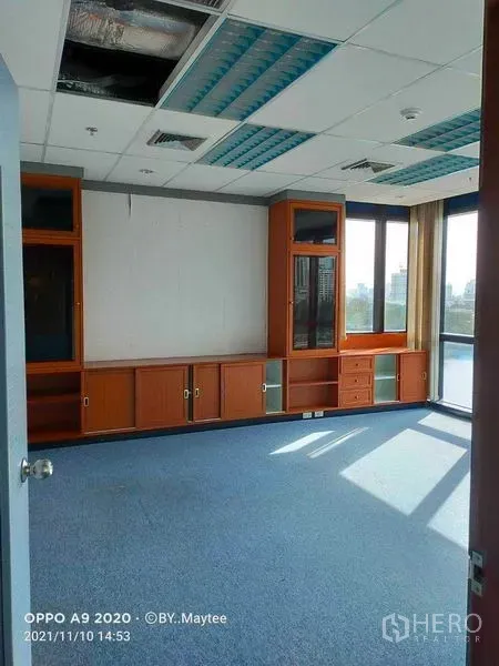 Office Space for rent in Watthana, Bangkok - Corner private office featuring built-in wooden cabinets, large windows and blue carpet flooring with city outlooks.