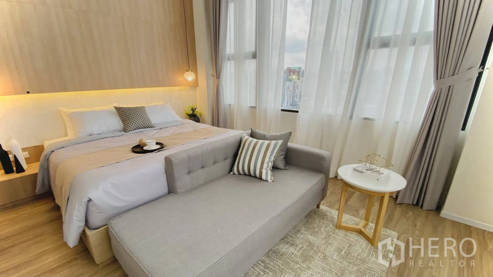 Condominium for rent or sale in Khlong Toei, Bangkok - Master bedroom with large windows, soft lighting, and a daybed-style sofa.