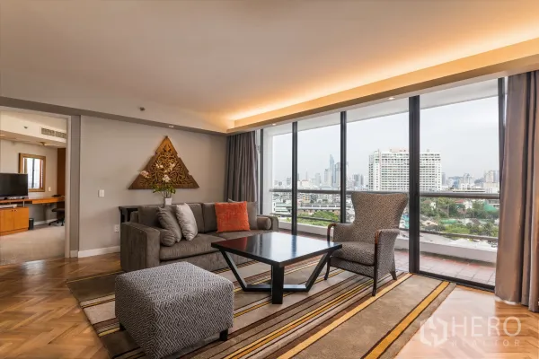 公寓 出租在Yan Nawa, Bangkok - 客厅，沙发和地毯，落地玻璃门通向阳台，眺望天际线。