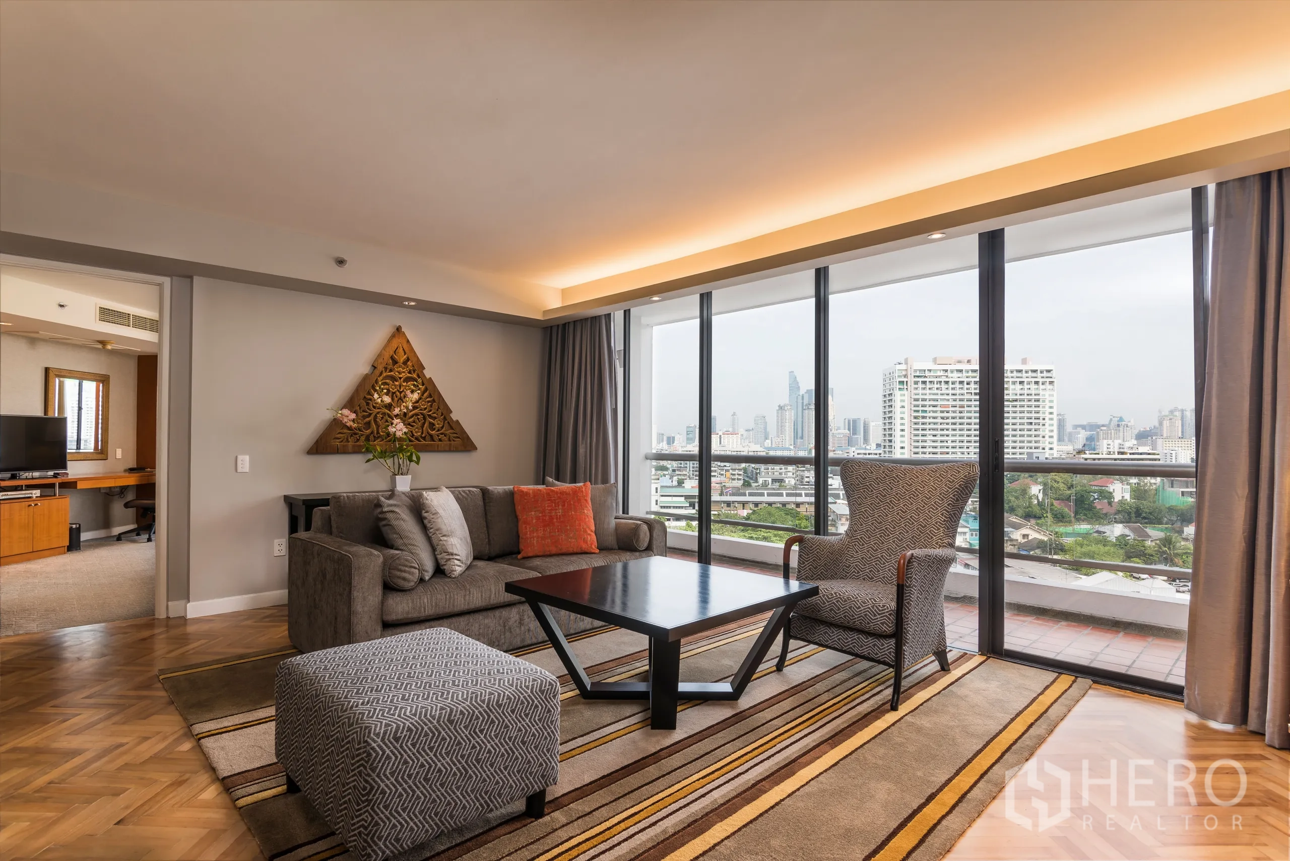 公寓 出租在Yan Nawa, Bangkok - 客厅，沙发和地毯，落地玻璃门通向阳台，眺望天际线。