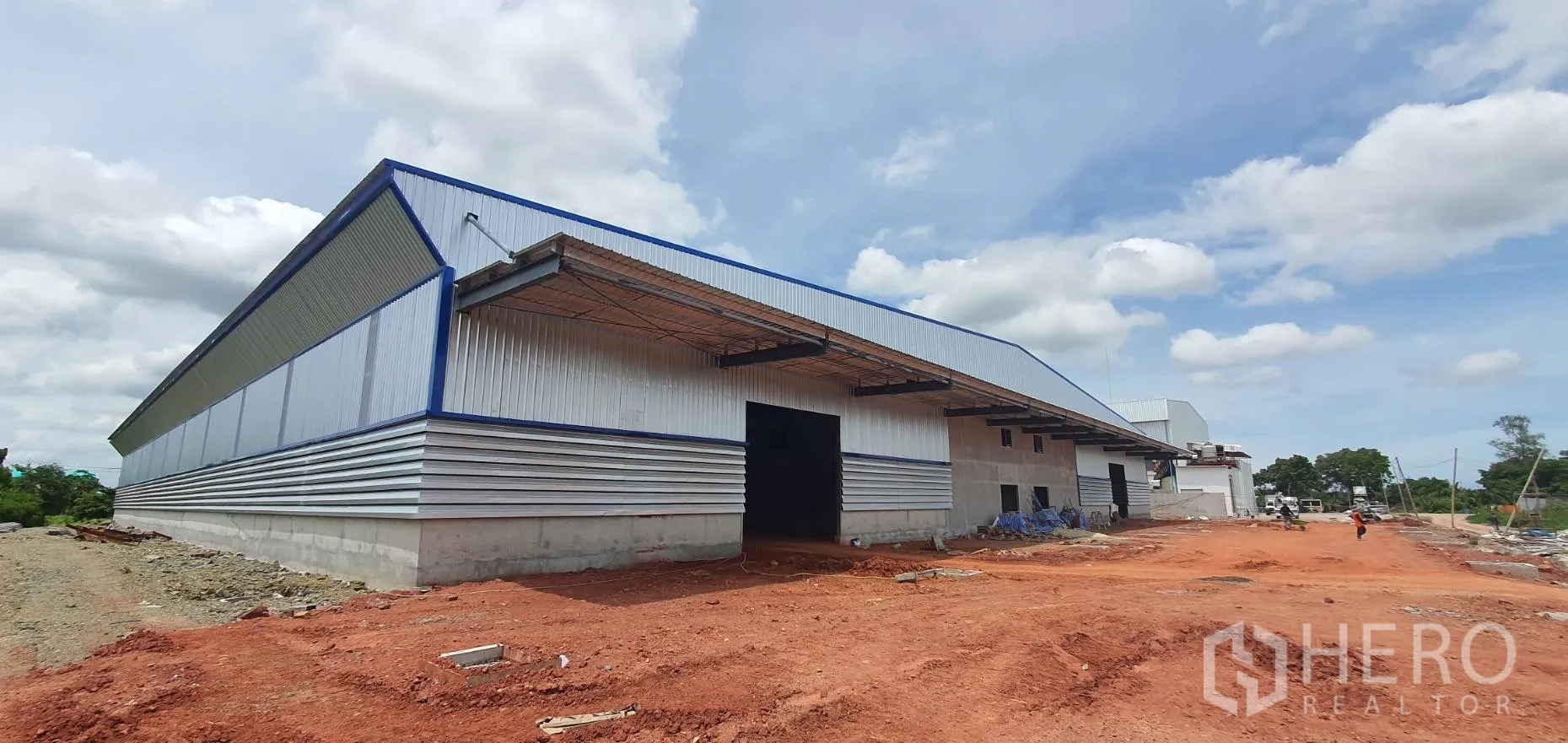 Warehouse for rent in Mueang Samut Sakhon, Samut Sakhon - Exterior view of a large warehouse with multiple loading bays, wide yard, and tall gable roof.