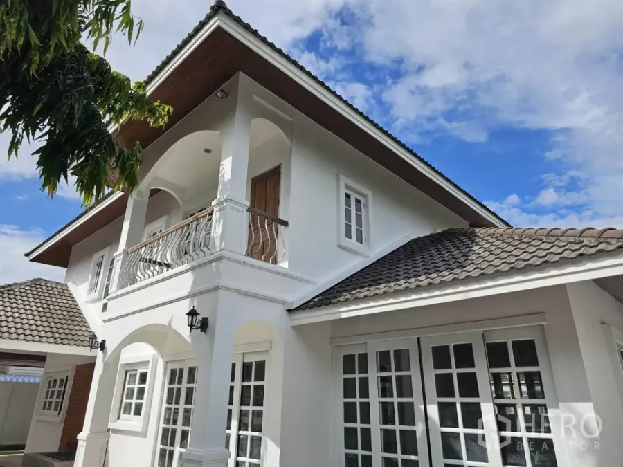 Detached House for rent in Phra Khanong, Bangkok - Corner exterior showing arched balcony, white walls and tiled roof of the Phra Khanong detached home.