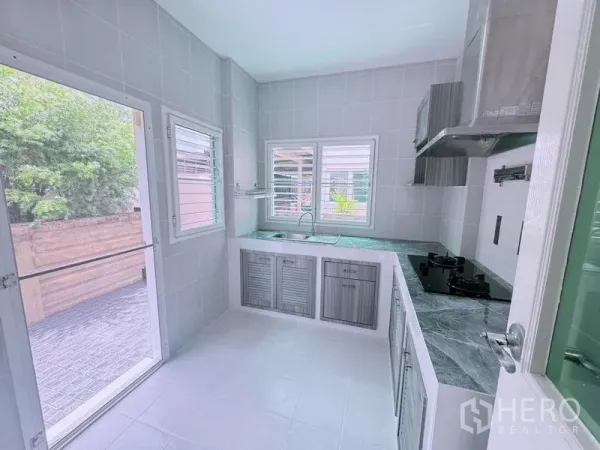 บ้าน ให้เช่าในPrawet, Bangkok - ห้องครัวปูกระเบื้องสว่าง เคาน์เตอร์รูปตัวแอล เตาแก๊ส เครื่องดูดควัน พร้อมหน้าต่างและประตูออกลาน
