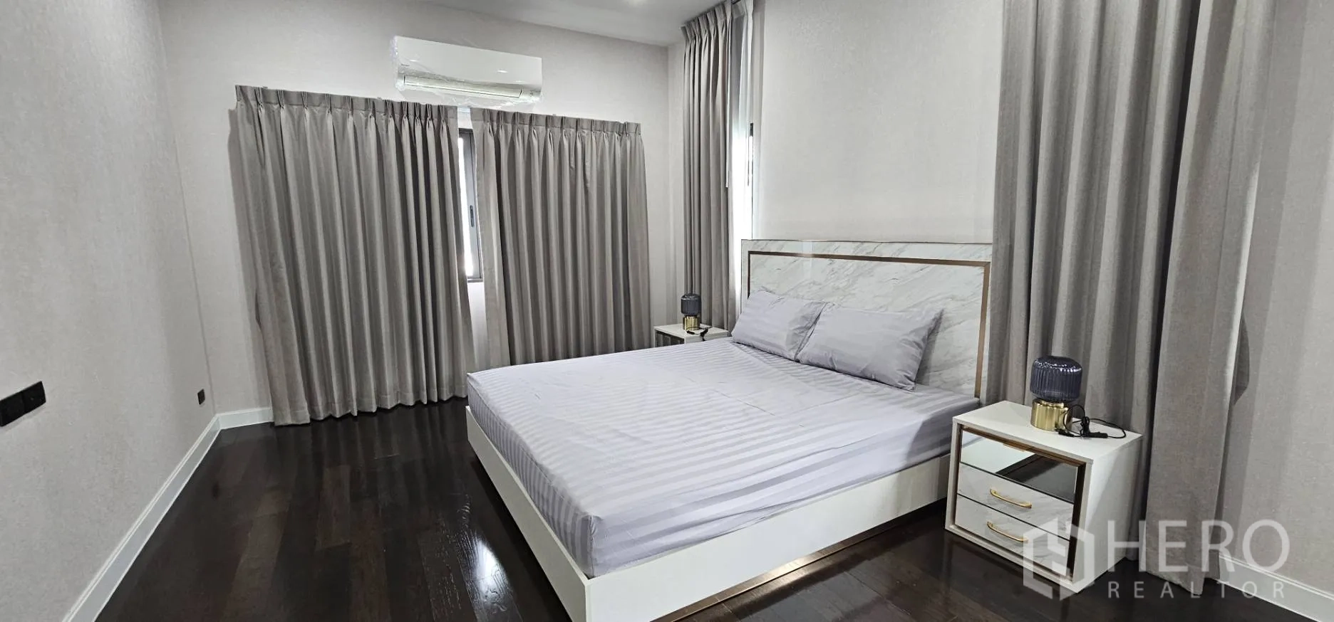 Detached House for rent in Bang Kapi, Bangkok - Bright bedroom with marble-style headboard and bedside tables.