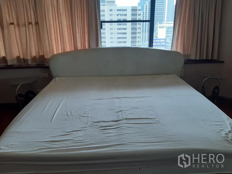 Condominium for rent in Khlong Toei, Bangkok - Primary bedroom with king bed, curtain-lined windows and skyline outlook.