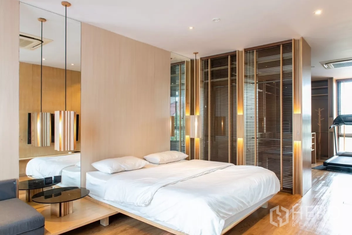Townhouse for rent in Lat Phrao, Bangkok - Spacious master bedroom with platform bed, mirrored wall and wood accents.