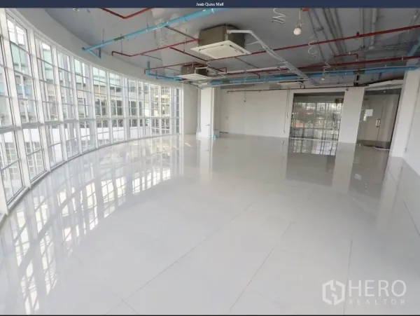 Office Space for rent in Khlong Toei, Bangkok - Open-plan office with curved floor-to-ceiling windows, glossy tile floors, and exposed ceiling services.