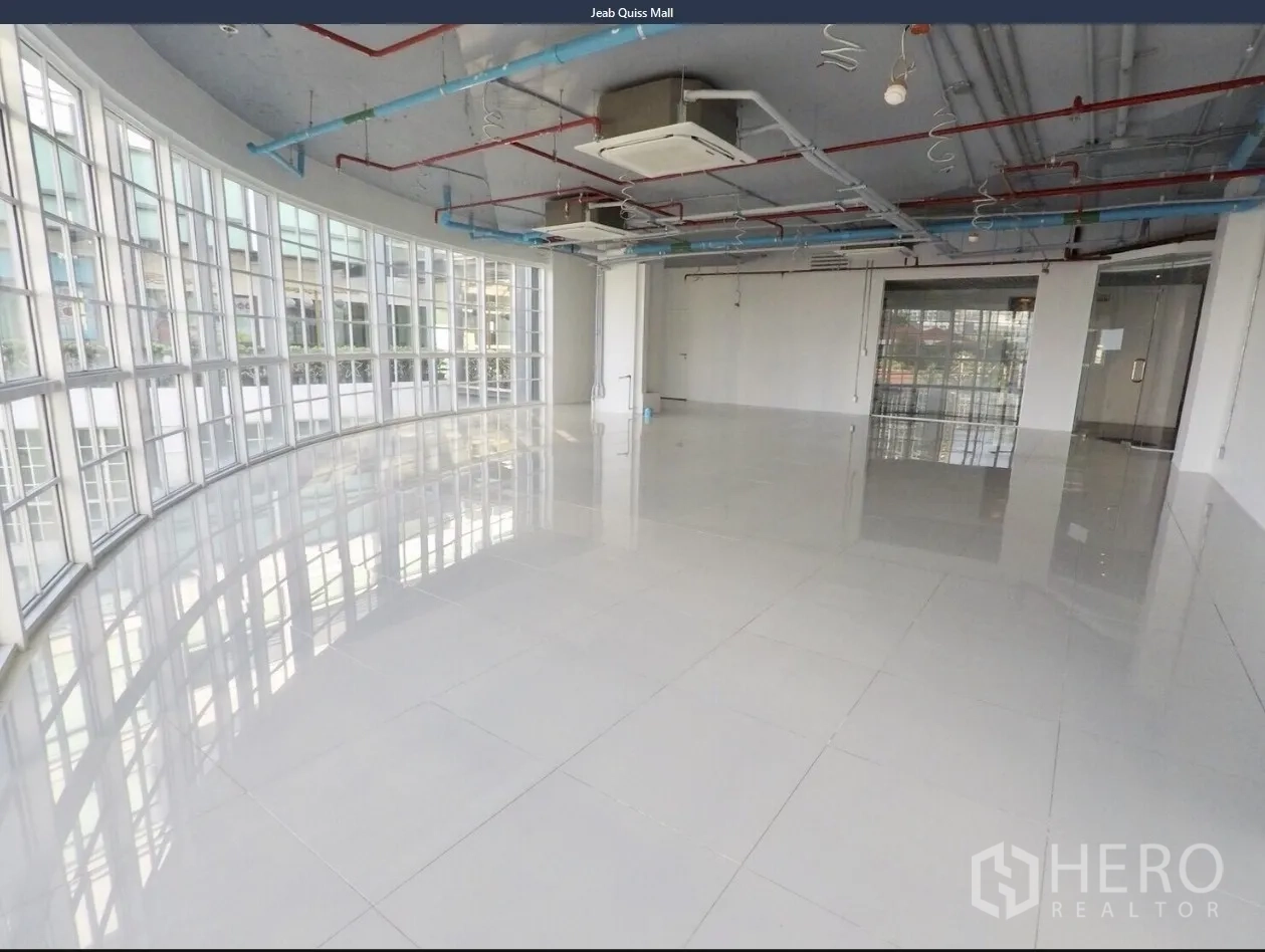 Office Space for rent in Khlong Toei, Bangkok - Open-plan office with curved floor-to-ceiling windows, glossy tile floors, and exposed ceiling services.