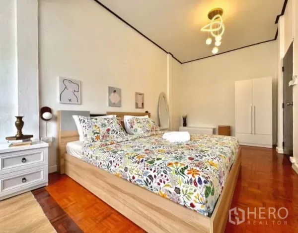 联排别墅 出租在Watthana, Bangkok - 宽敞卧室，花卉床品、吊灯、衣柜与拼花木地板