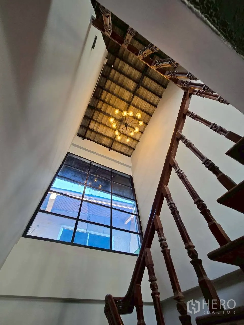 独栋房屋 for rent in Phra Khanong, Bangkok - 挑高楼梯间，设吊灯与大型网格窗。