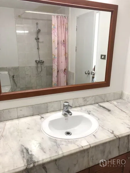 Condominium for rent or sale in Watthana, Bangkok - Guest bathroom with marble counter, sink, mirror and shower.