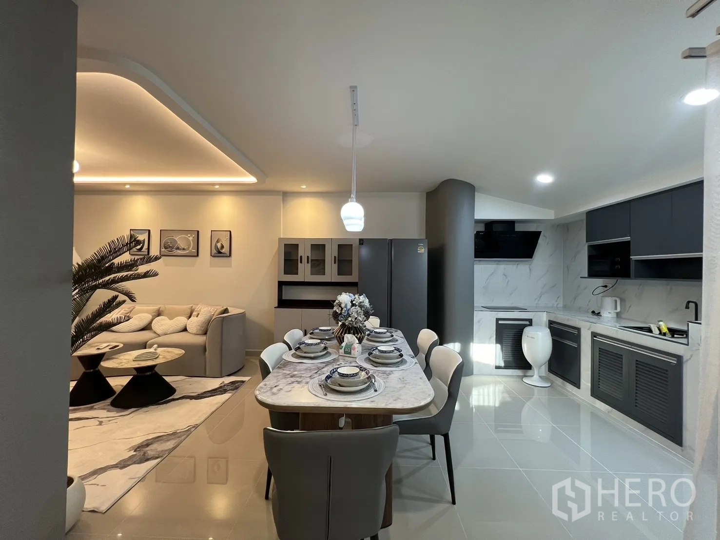 联排别墅 for rent in Bang Phli, Samut Prakan - 从客厅望向厨房，极简橱柜与吊灯相映成趣。