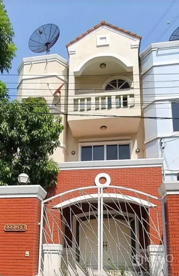 Townhouse for rent in Huai Khwang, Bangkok - Three-storey townhouse exterior with arched balcony, red brick wall and secure front gate in Huai Khwang.