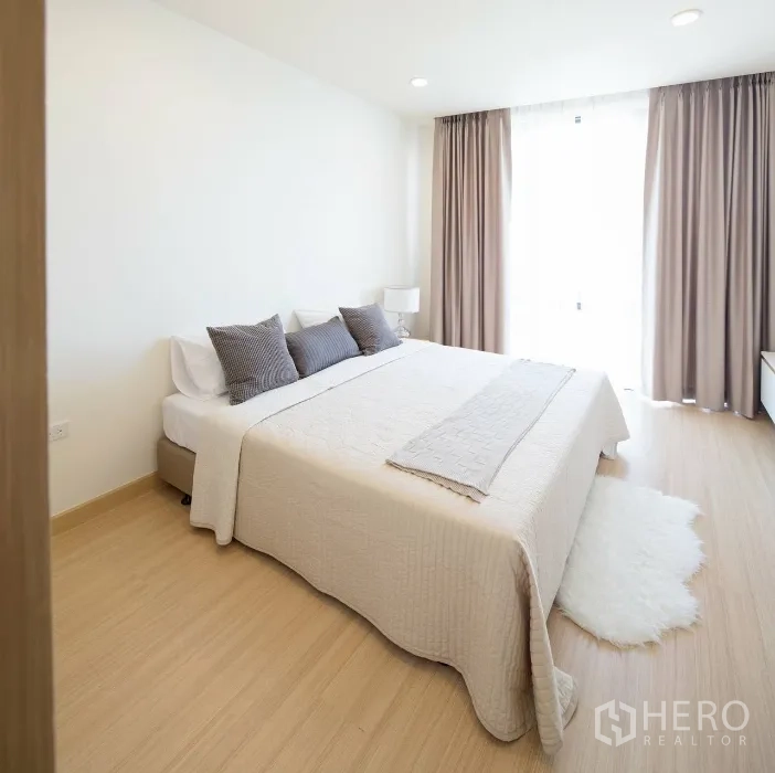 คอนโด ให้เช่าในWatthana, Bangkok - ห้องนอนที่สองมีหน้าต่างบานใหญ่ ผ้าม่านสีเบจ พรมขนฟู และพื้นไม้โทนอุ่น