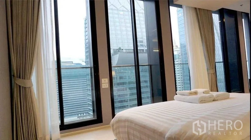 Condominium for rent in Pathum Wan, Bangkok - Bedroom with expansive floor-to-ceiling windows offering Bangkok city views.